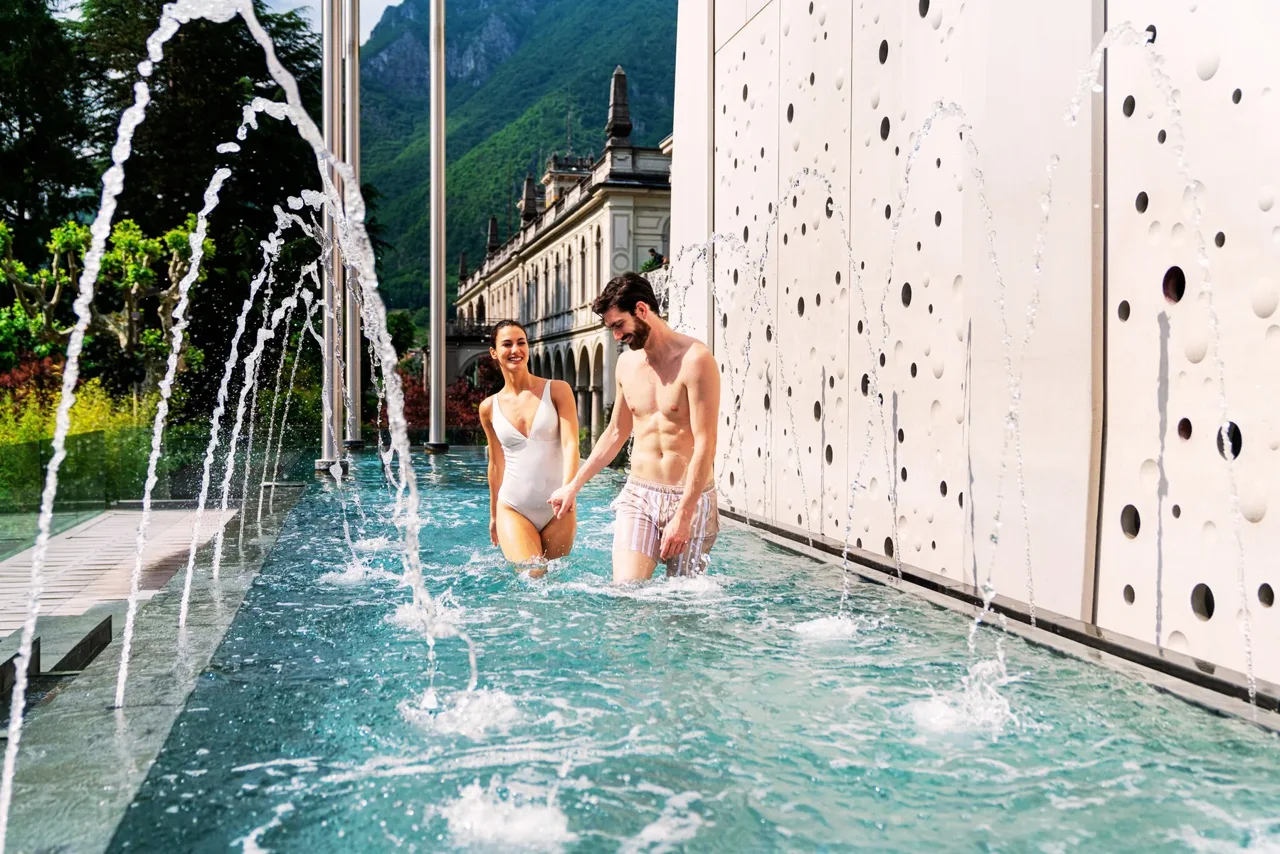 Coppia nella piscina esterna di QC Terme San Pellegrino, centro esterno distinto dalle Spa T’Ami